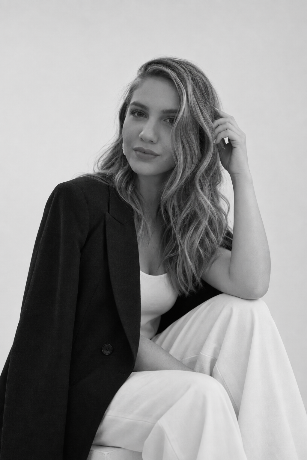 Portrait of a seated woman in a black blazer and white trousers